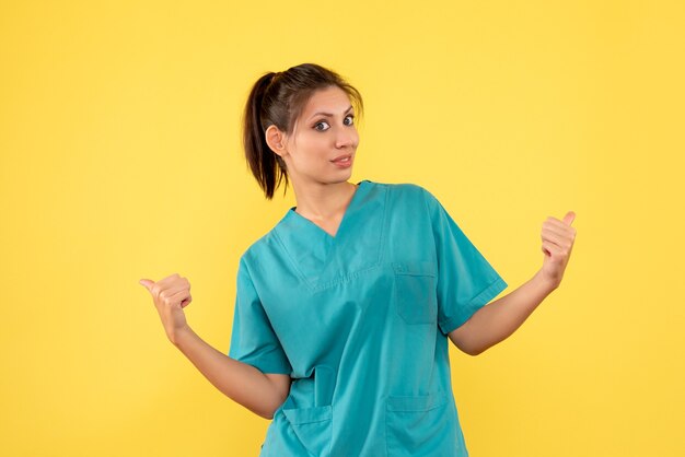 Front view female doctor in medical shirt on yellow background