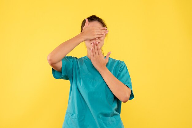 Front view female doctor in medical shirt on yellow background