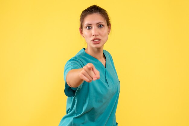 Front view female doctor in medical shirt on yellow background