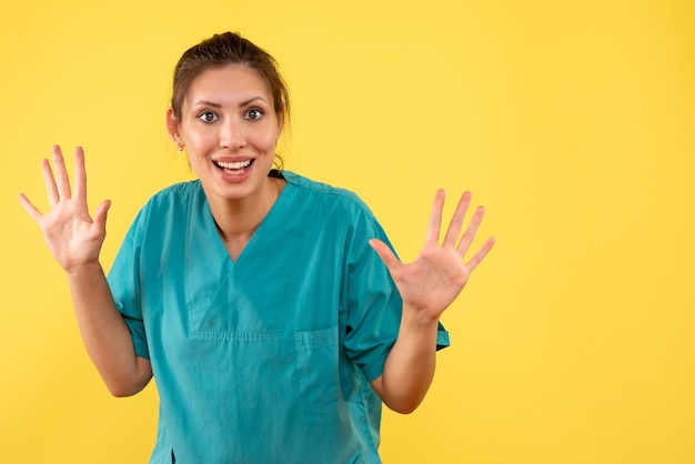 Medico femminile di vista frontale in camicia medica su una priorità bassa gialla