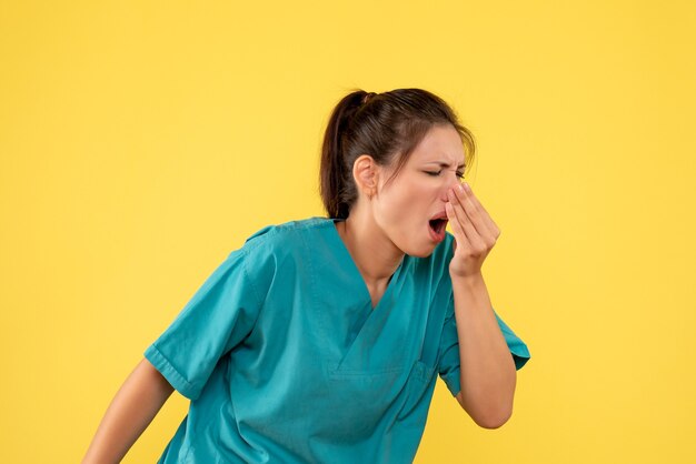 Front view female doctor in medical shirt on yellow background