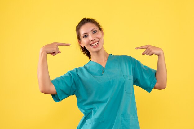 Front view female doctor in medical shirt on yellow background