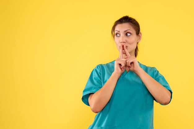 Front view female doctor in medical shirt on yellow background