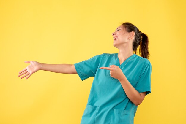 Front view female doctor in medical shirt on yellow background