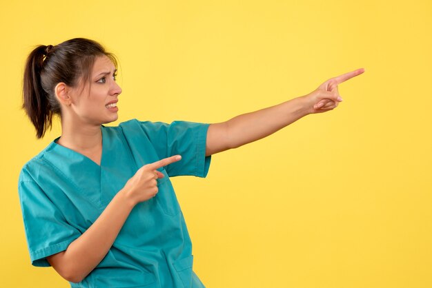 Medico femminile di vista frontale in camicia medica su una priorità bassa gialla