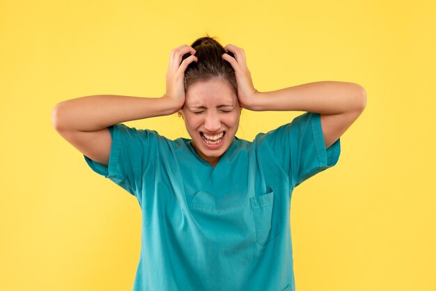 Front view female doctor in medical shirt on yellow background