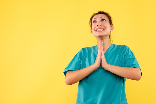 Foto gratuita medico femminile di vista frontale in camicia medica su una priorità bassa gialla