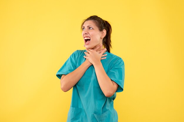 Front view female doctor in medical shirt on yellow background