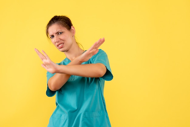 Front view female doctor in medical shirt on yellow background