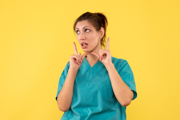 Front view female doctor in medical shirt on yellow background