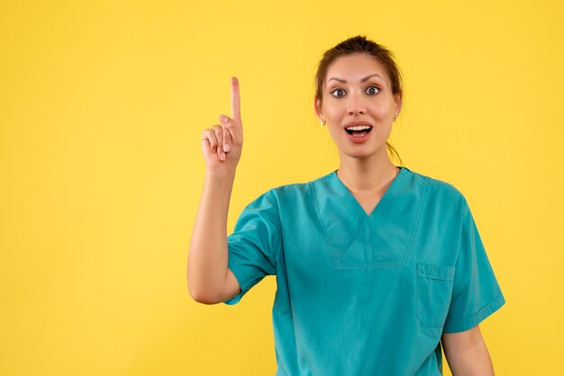 Front view female doctor in medical shirt on yellow background