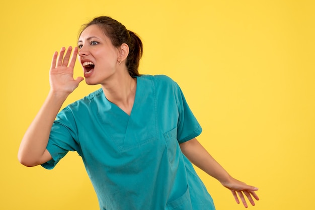 Front view female doctor in medical shirt on yellow background