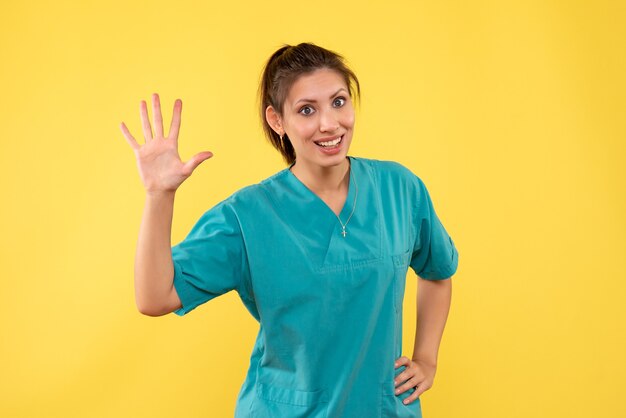 Front view female doctor in medical shirt on yellow background