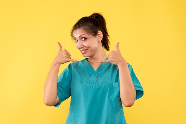 Front view female doctor in medical shirt on yellow background