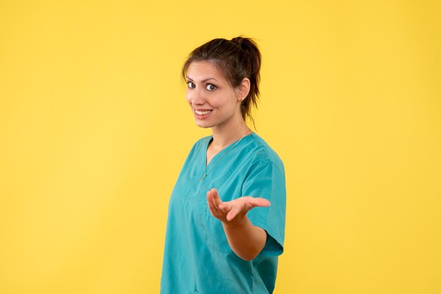 Front view female doctor in medical shirt on yellow background