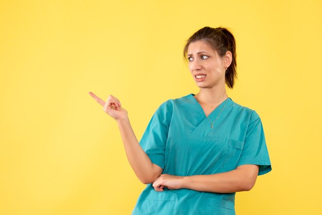 Front view female doctor in medical shirt on yellow background