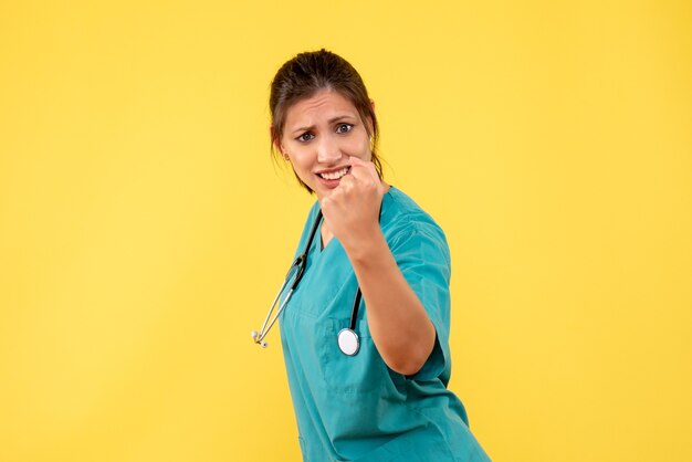 Front view female doctor in medical shirt on yellow background