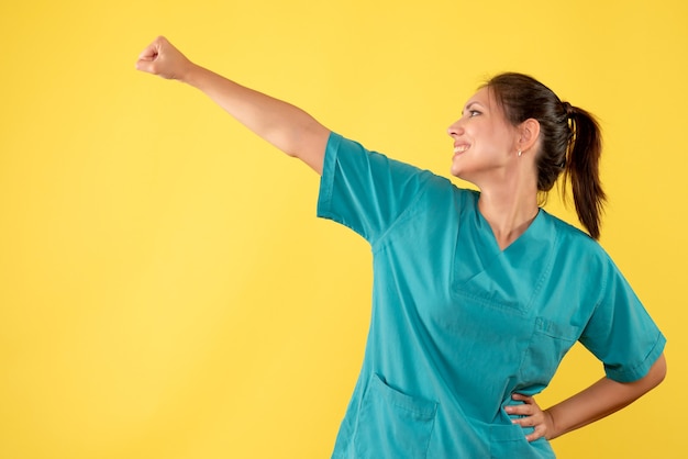 Front view female doctor in medical shirt on yellow background