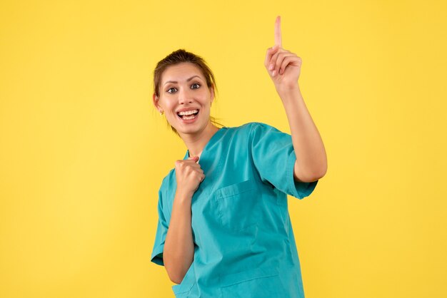 Front view female doctor in medical shirt on yellow background