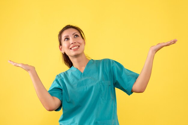 Front view female doctor in medical shirt on yellow background