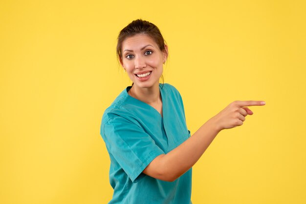 노란색 배경에 의료 셔츠에 전면보기 여성 의사