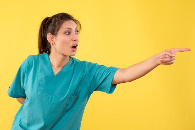 Front view female doctor in medical shirt on yellow background