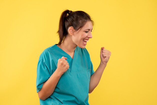 Front view female doctor in medical shirt on yellow background