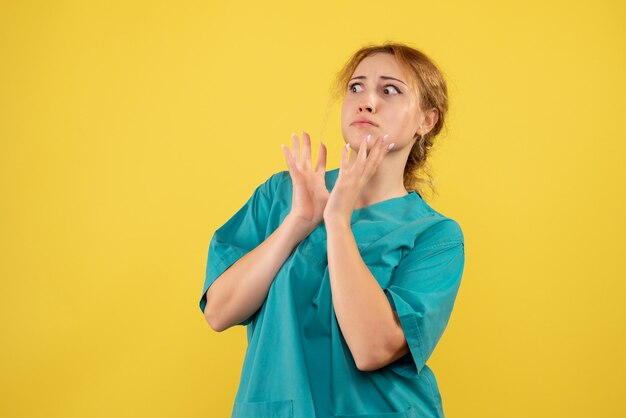 Вид спереди женщина-врач в медицинской рубашке на желтом столе медсестра covid-19 цвета здоровья медика