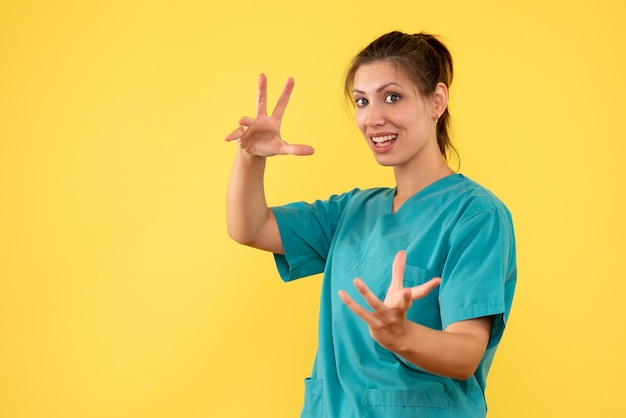 Front view female doctor in medical shirt on yellow desk covid hospital color nurse health virus medic