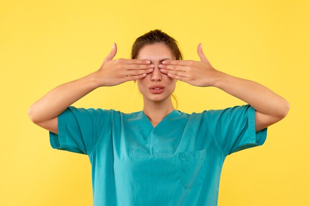 Front view female doctor in medical shirt on yellow desk virus hospital nurse health illness color medic