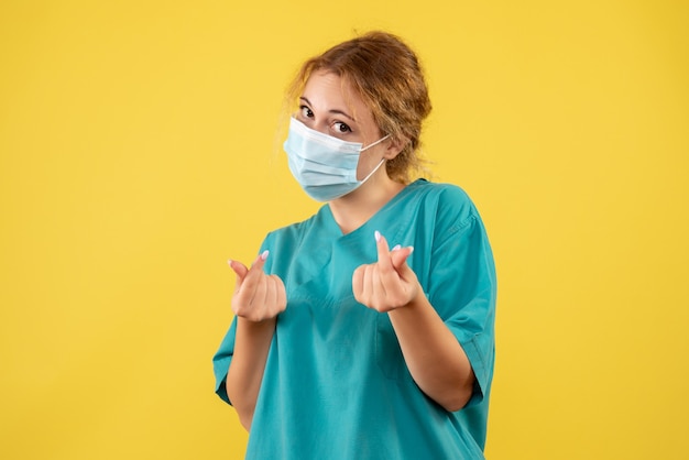 Front view of female doctor in medical suit and mask on yellow wall