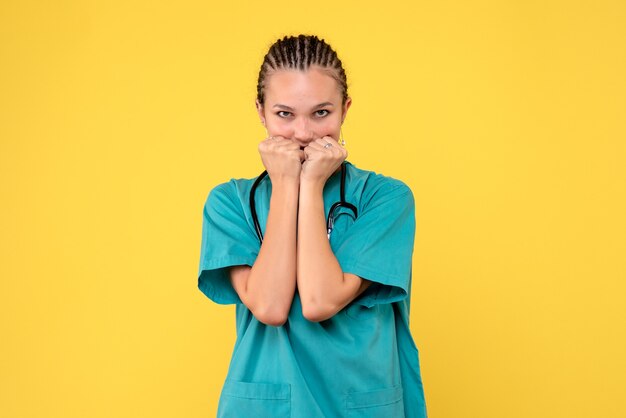 Front view of female doctor in medical suit nervous on a yellow wall