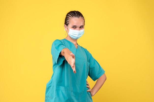 노란색 벽에 의료 소송 및 멸균 마스크 여성 의사의 전면보기