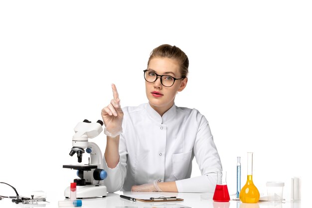 Front view female doctor in medical suit wearing gloves due to covid on the white space