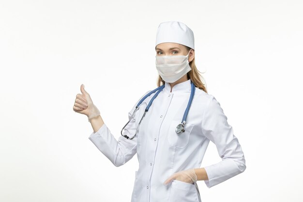ライトホワイトデスク病コビパンデミックウイルスのコロナウイルスによるマスクを着用した医療スーツの正面図の女性医師
