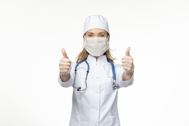 Вид спереди женщина-врач в медицинском костюме в маске из-за коронавируса на свете вирус болезни белой стены covid - болезнь пандемического заболевания