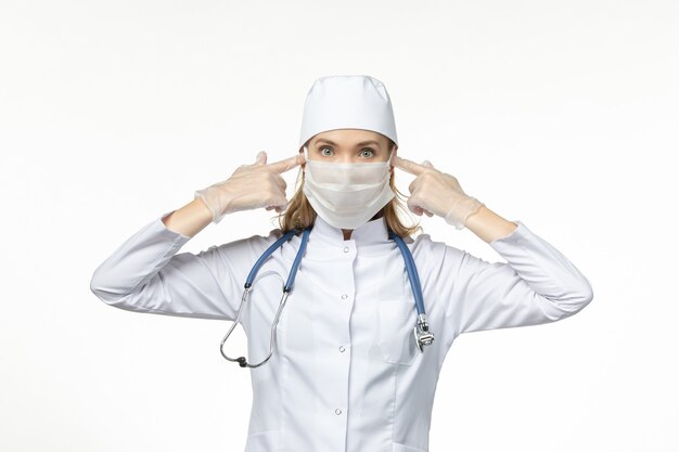 라이트 데스크에 코로나 바이러스로 인해 마스크와 장갑을 끼고 의료 복을 입은 여성 의사 전면보기 covid- pandemic disease virus disease