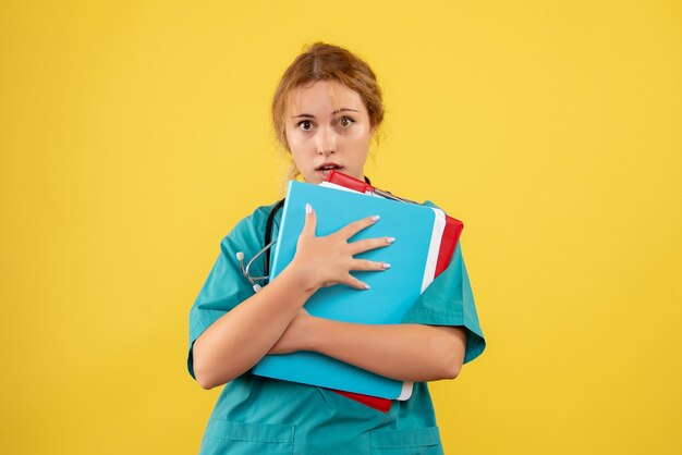 Front view of female doctor in medical suit with analysis on the yellow wall