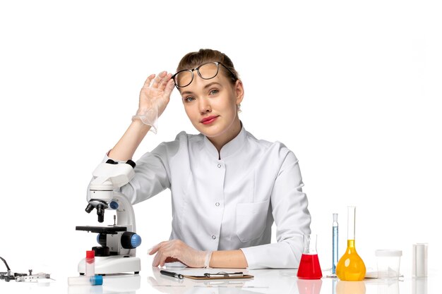 Front view female doctor in medical suit with gloves due to covid on a white space