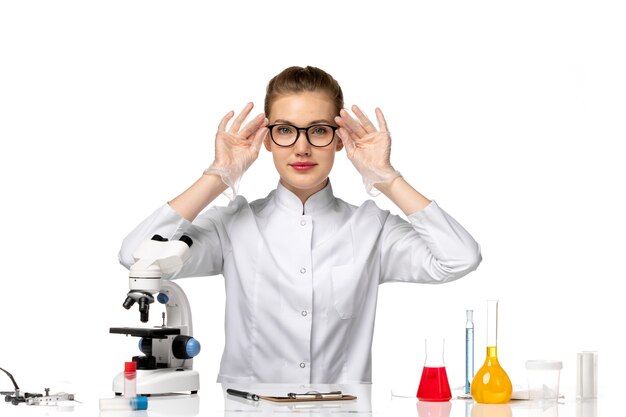 Front view female doctor in medical suit with gloves due to covid on white space