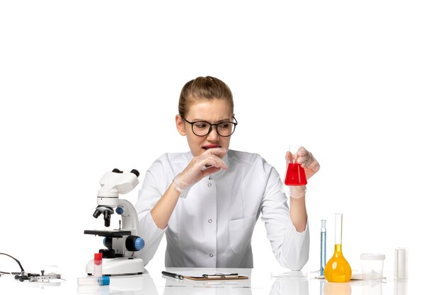 Front view female doctor in medical suit with gloves holding solution on light white space