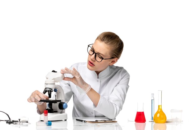 Front view female doctor in medical suit with gloves in working process on light white space