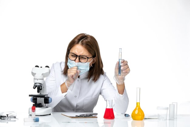 Front view female doctor in medical suit with mask due to covid coughing on white space