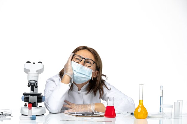 Front view female doctor in medical suit with mask due to covid dreaming on white space