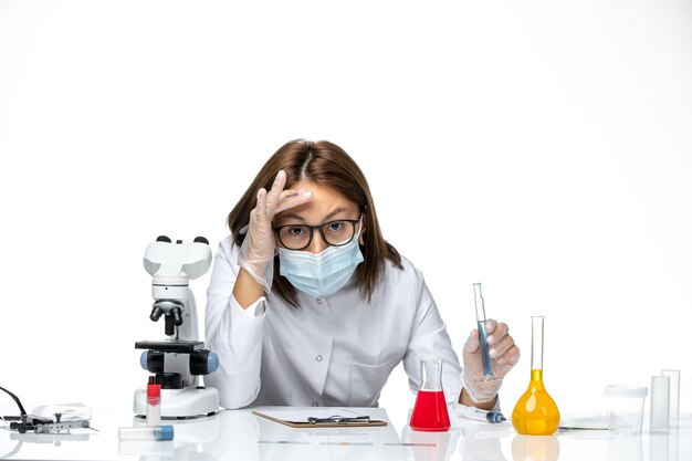 Front view female doctor in medical suit with mask due to covid in working process on white space