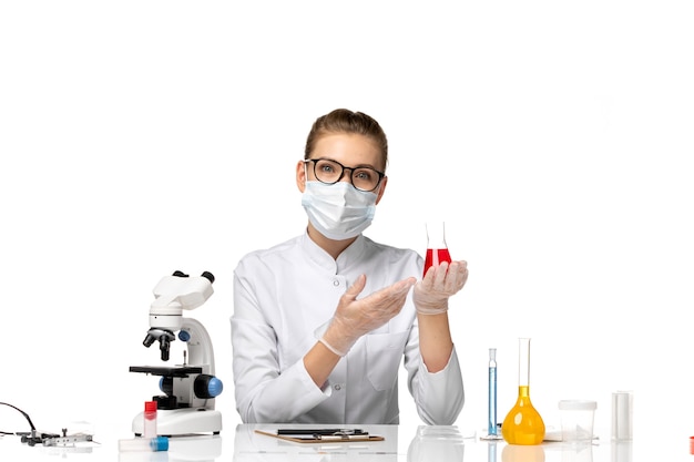 Вид спереди женщина-врач в медицинском костюме с маской из-за covid, работающего с растворами на белом пространстве