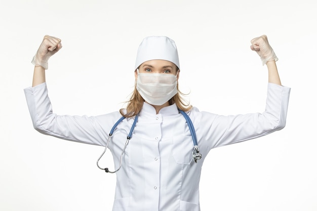 밝은 흰색 벽 질병 유행성 코로나 바이러스에 코로나 바이러스 구부러짐으로 인해 마스크와 장갑이있는 의료 소송의 전면보기 여성 의사