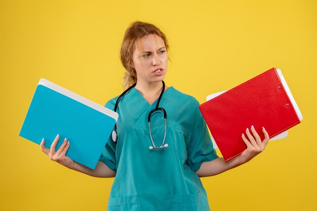 노란색 벽에 서류 및 분석 의료 소송에서 여성 의사의 전면보기