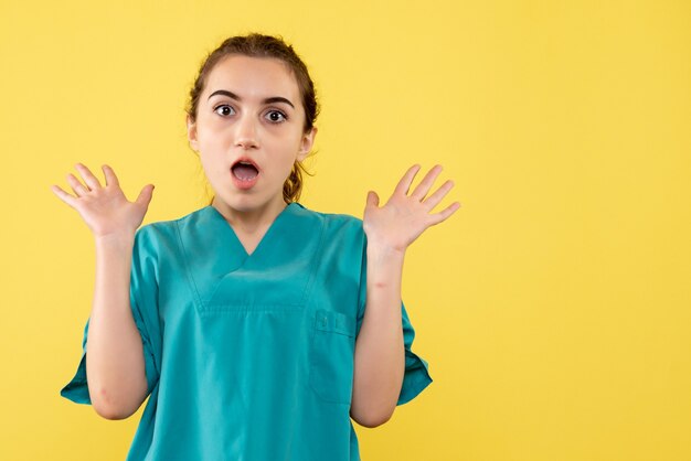 Front view of female doctor in medical suit on yellow wall