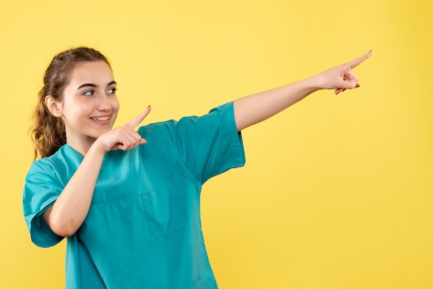 Vista frontale della dottoressa in tuta medica sulla parete gialla